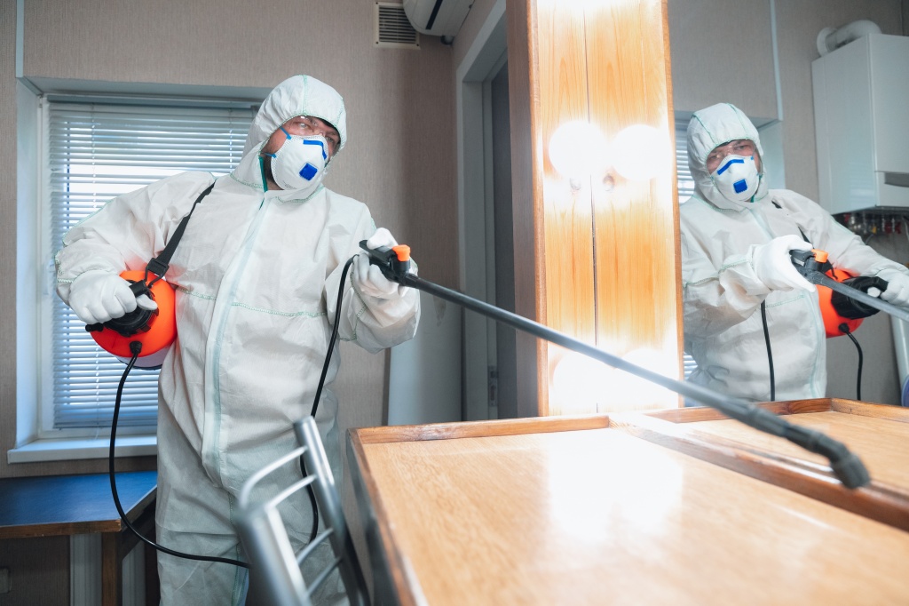 coronavirus-pandemic-disinfector-in-a-protective-suit-and-mask-sprays-disinfectants-in-the-house-or-office.jpg
